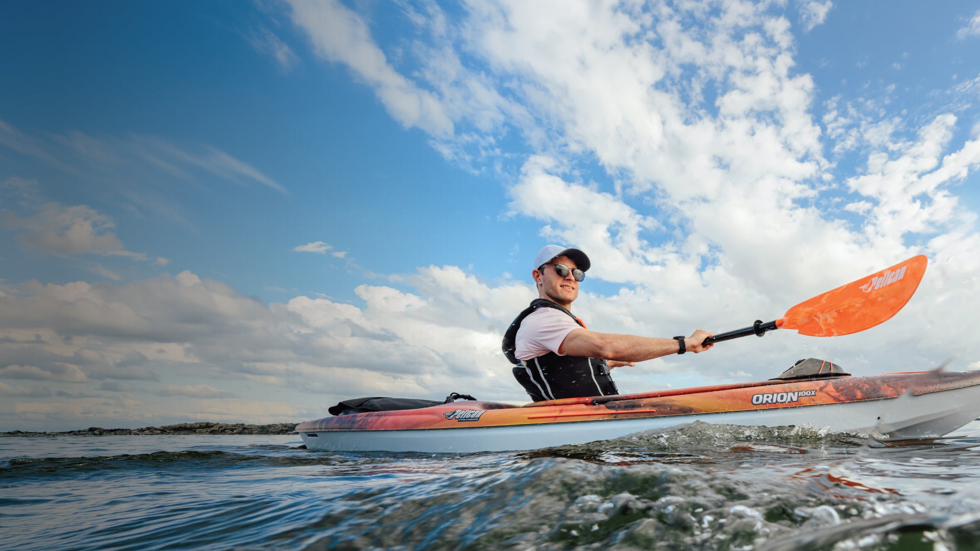 A man smiling while paddling in a Pelican Orion 100X