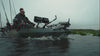 A man navigating a fully equipped Wilderness Systems fishing kayak with dual screens and trolling motor on open water.
